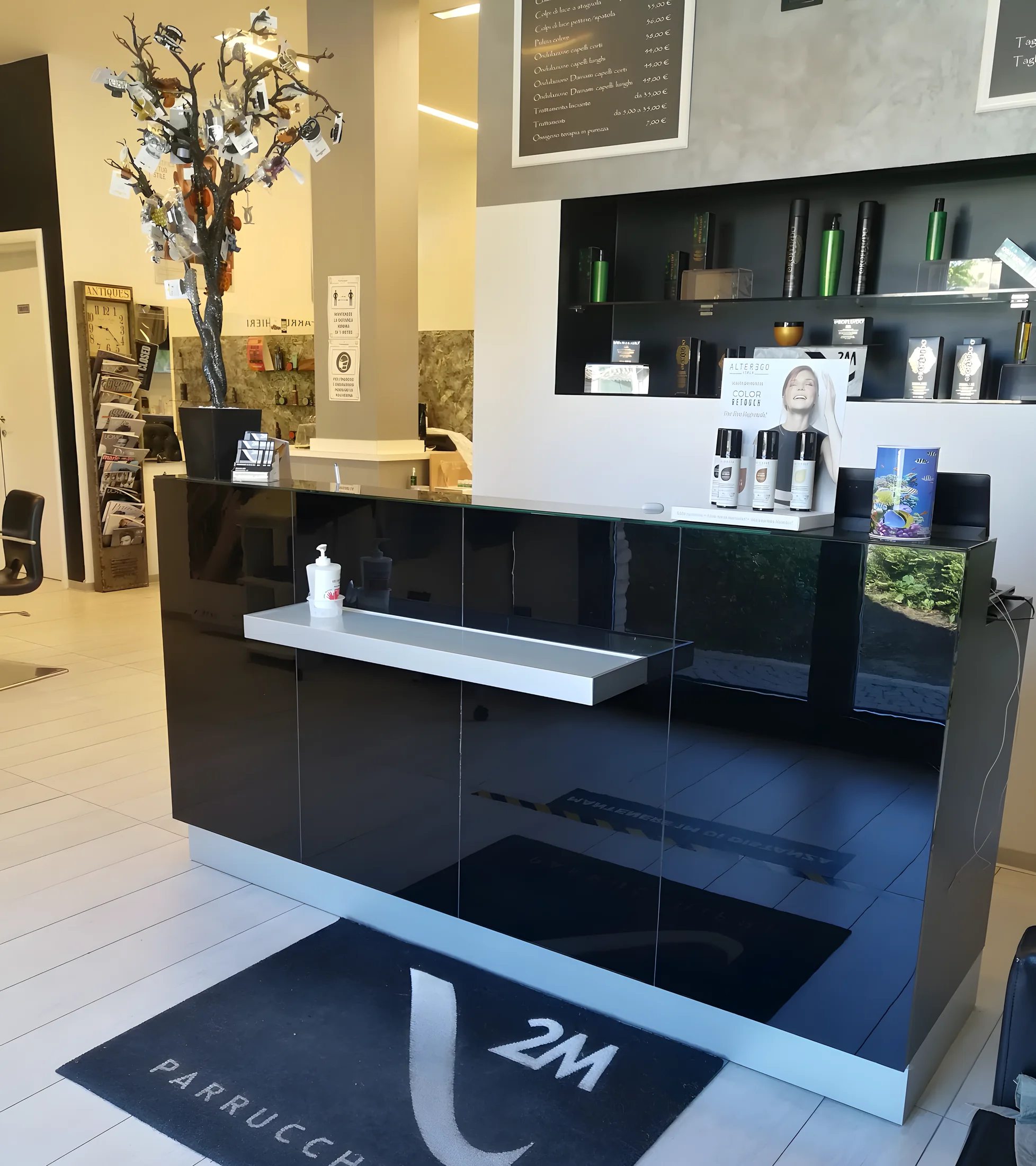 L'ingresso del salone: il banco nero lucido e il tappeto con il marchio 2M