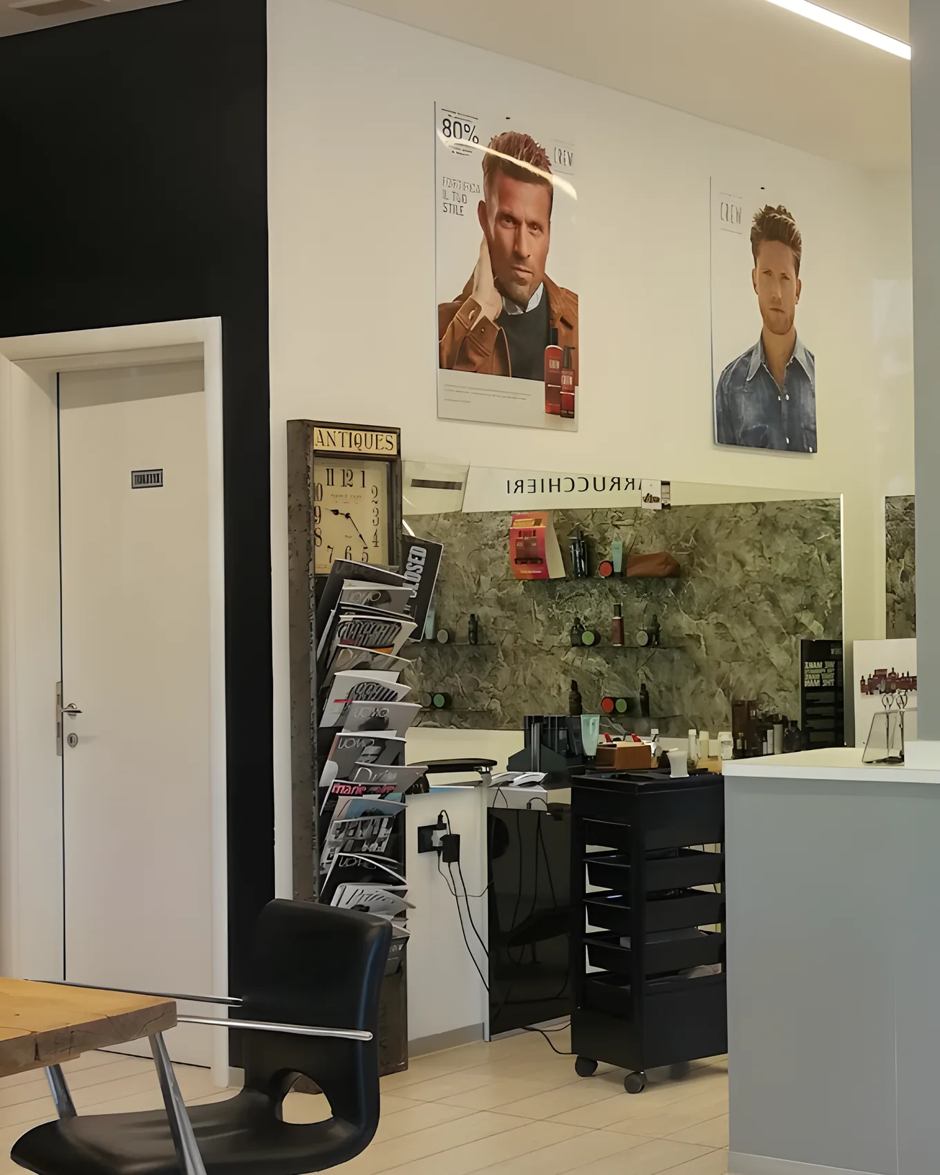 Il salone 2M dal lato delle postazioni: i manifesti uomo alla parete, la mensola dei prodotti e la poltrona
